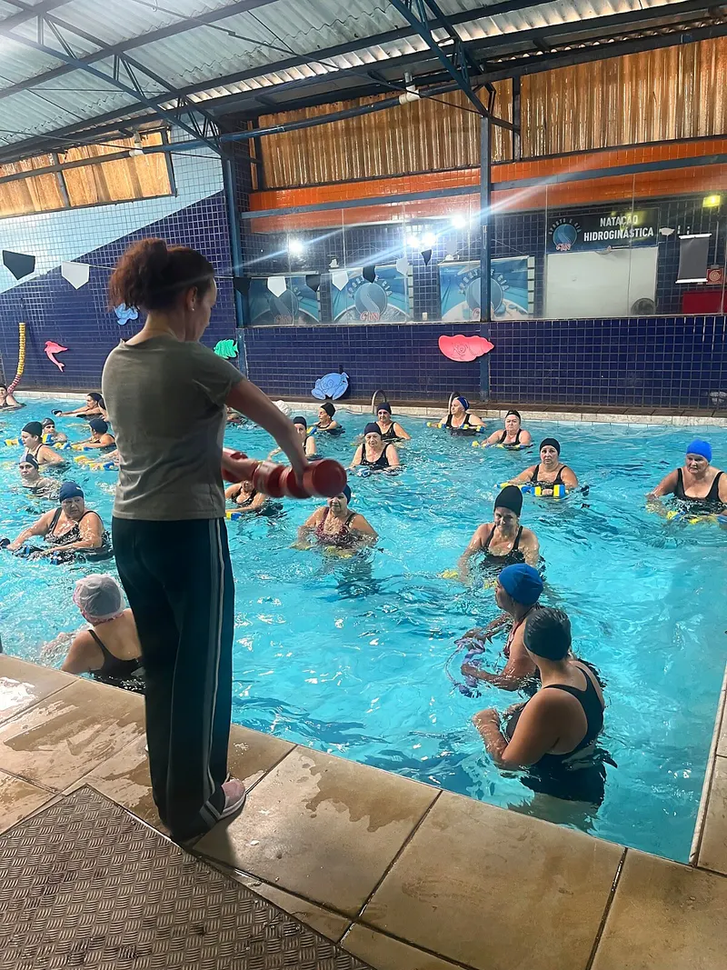 Aula de hidroginástica com professora orientando alunas na piscina